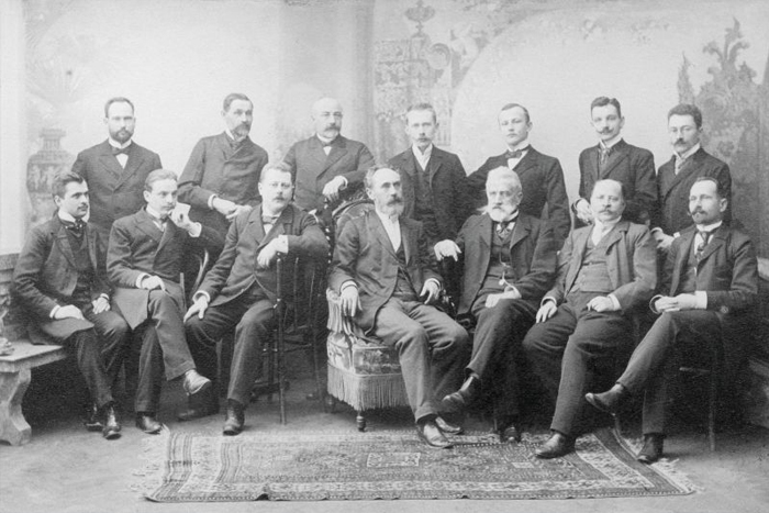 Men in suits pose for a photograph. Vintage photo, black and white.