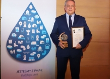 The Vice president of the Kraków Waterworks proudly holds diploma and  statuette.