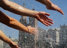 Hands turned towards floating water drops. In the background you can see St. Mary's Church.